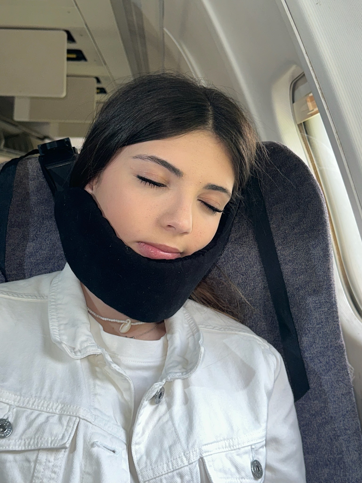 Nap-Kit travel pillow attached to airplane seat headrest using two clamps